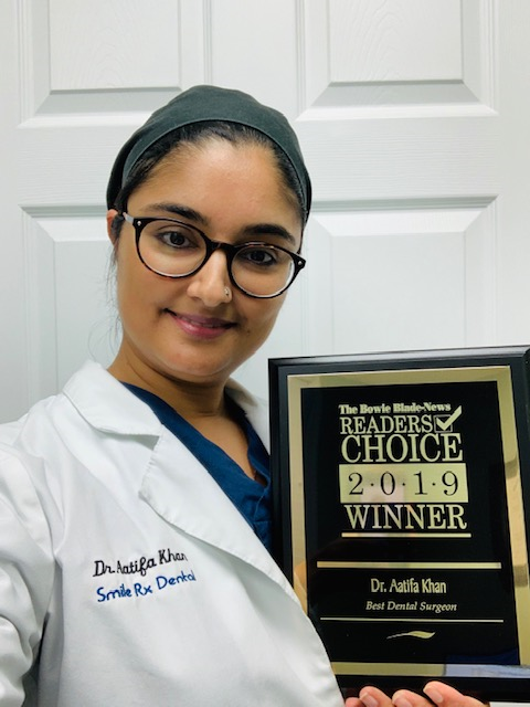 Dr. Khan posting with the 2019 Best Dentist Award plaque